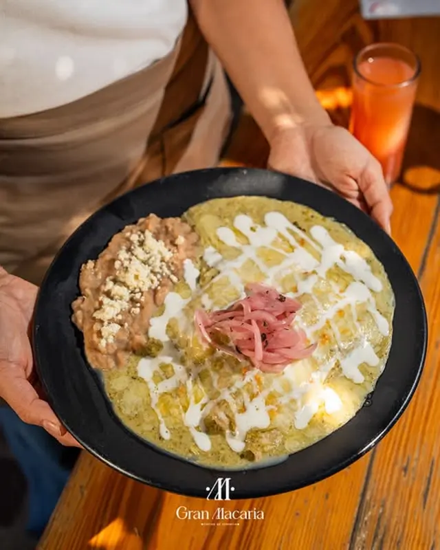 Chilaquiles verdes con crema y cebolla morada.