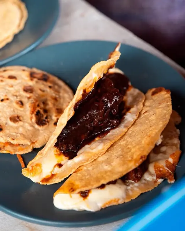 Quesadillas doradas con salsa oscura y queso fundido.